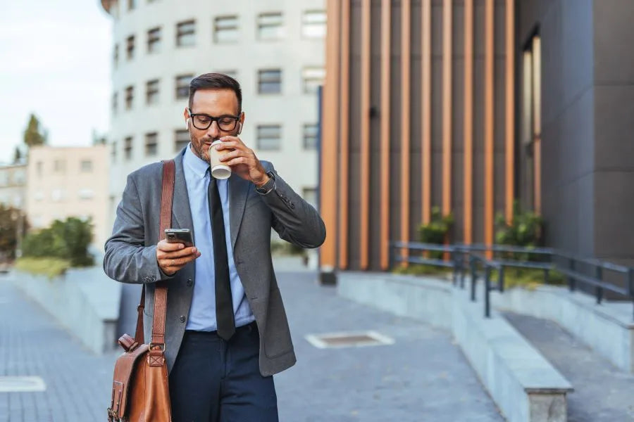 man on his way to the office checks smartphone; remote access to the door lock via app is possible at any time