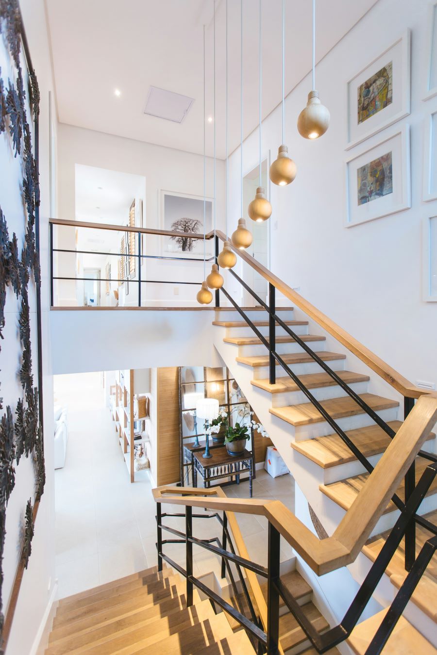 Modern staircase with wooden steps and black metal railings in a well-lit room.
