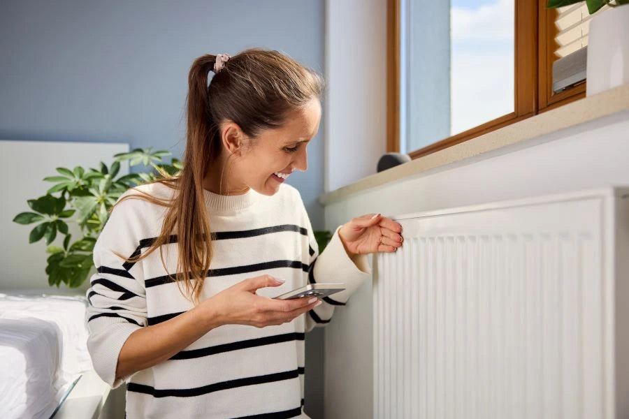 woman checks heater temperature by smartphone; control target temperature and heating schedules via app