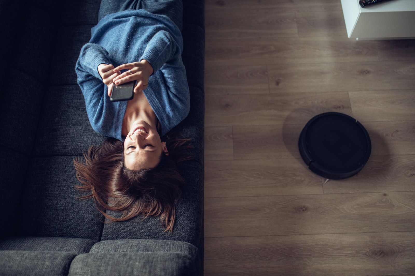 woman relaxing on a sofa with smartphone, controlling her smart home securely via the Z‑Wave communication standard
