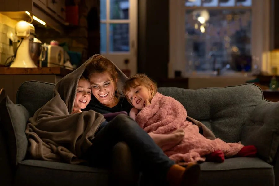 KNX smart home – mother with daughters on a sofa, controlling lighting and heating via powerful KNX building systems technology