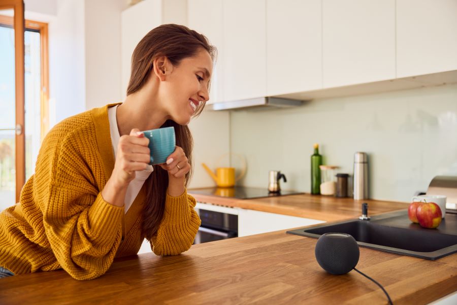 woman smiles with coffee in the kitchen; Alexa Smart Home responds to Shelly voice control 