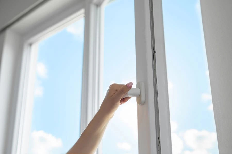Save heating costs – woman’s hand on a window handle; airing with Shelly BLU Door/Window prevents unnecessary heat loss