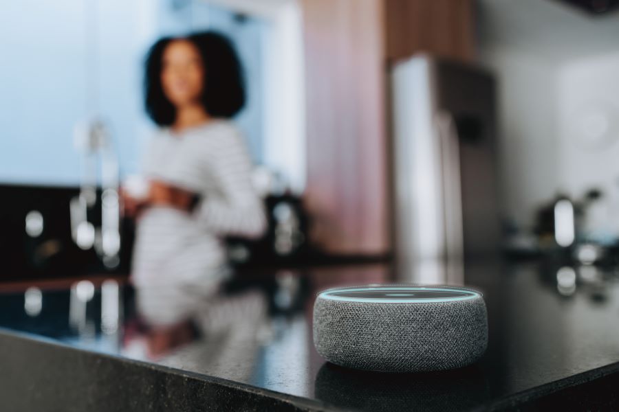Woman in kitchen talks to Alexa box, remotely controls Shelly devices via voice command in Alexa Smart Home 