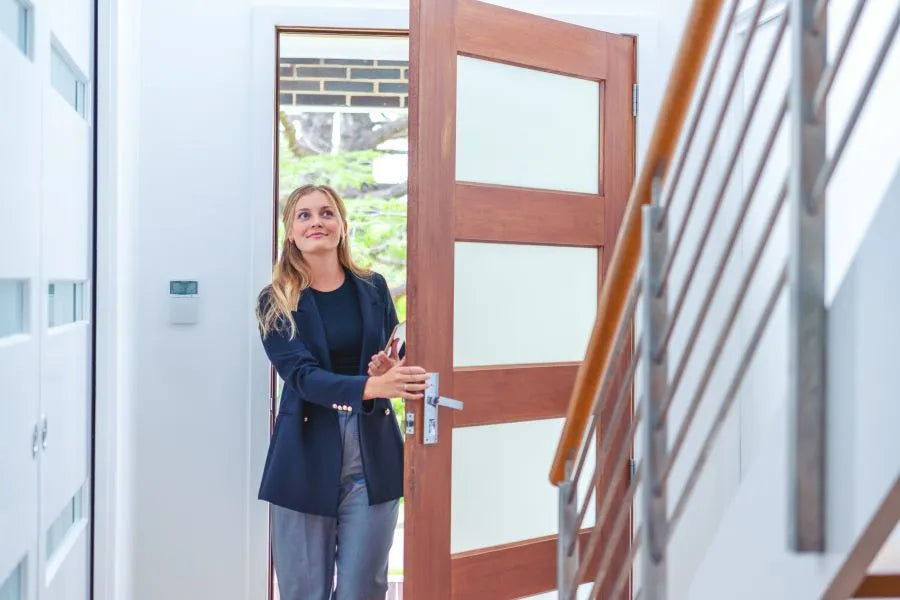 woman opens the front door; door contact reports presence and triggers automations for lights and heating.